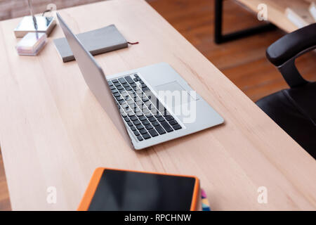 Opened slim and silver laptop placed on wooden office table Stock Photo