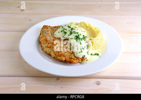 Chopped cutlet in breading with mashed potato and cream sauce Stock Photo