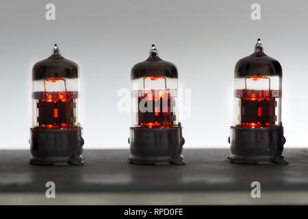 three orange vintage lighted amplifier tubes Stock Photo