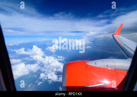 Arial view from internal cabin of aeroplane.Clouds in the sky and cityscapes though airplane window. Red aeroplane flying. Stock Photo