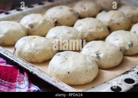 Baking tray with round uncooked cross buns on a wooden table. Selective focus. Stock Photo