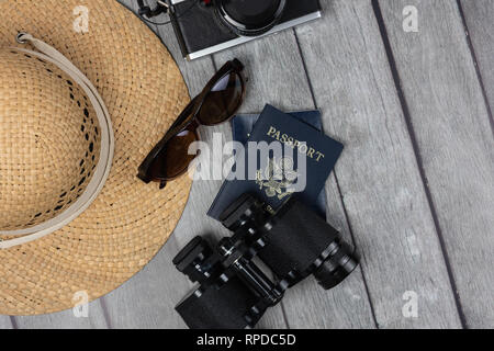 ladies travel concept with straw hat sunglasses two passports camera and binoculars on a grey weathered wood background Stock Photo