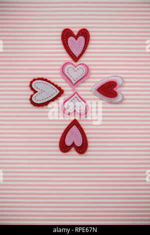 Felt hearts on a pink and white striped background Stock Photo