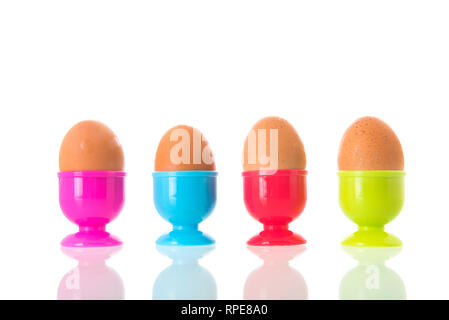 Colorful egg cups with eggs isolated over white background Stock Photo