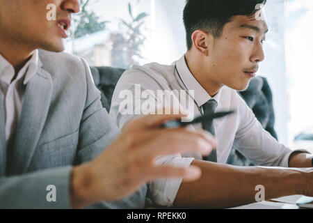 Businessman working on laptop with his colleague sitting by discussing. Two business associates at a restaurant. Stock Photo