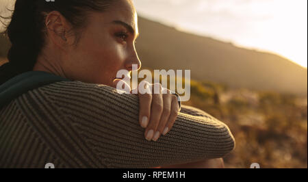 Close up of young woman taking break during hiking. Female hiker taking rest and thinking. Stock Photo