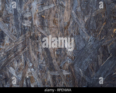 OSB boards are made of brown wood chips sanded into a wooden background. Top view of OSB wood veneer background, tight, seamless surfaces. Stock Photo