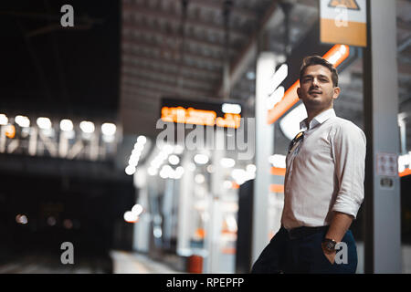Young attractive businessman waiting for train in metro or subway on modern stylish platform. Concept of commuting. Stock Photo