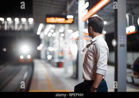 Young attractive businessman waiting for train in metro or subway on modern stylish platform. Concept of commuting. Stock Photo