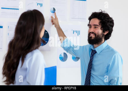 Turkish businessman explaining strategy to businesswoman at office of company Stock Photo