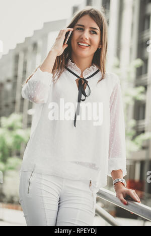 Attractive brunette businesswoman talking on mobile phone with client. - Image Stock Photo