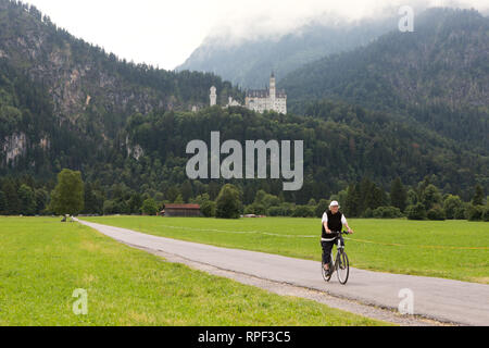 SCHWANGAU - Cyclist with the famous Neuschwanstein castle in the background. Stock Photo