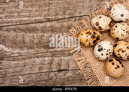 Several quail eggs on burlap on old wooden background with copy space for your text. Top view Stock Photo