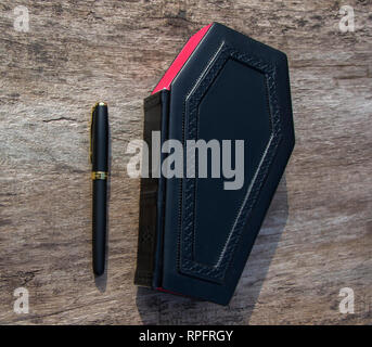 Leather book with cover in shape of Coffin. The book is captured closed and frontal while standing on the wooden table Stock Photo