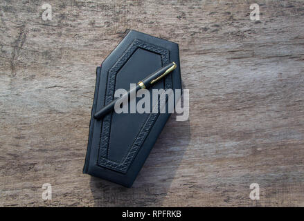 Leather book with cover in shape of Coffin. The book is captured closed and frontal while standing on the wooden table Stock Photo
