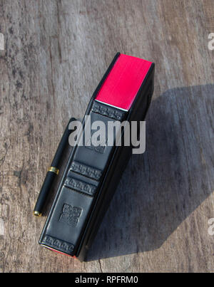 Leather book with cover in shape of Coffin. The book is captured closed and frontal while standing on the wooden table Stock Photo