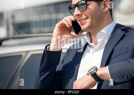Young man in sunglasses leaning on car answering phone call cheerful close-up Stock Photo