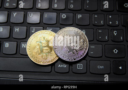 A pair of gold and silver bitcoin coins on a desktop computer keyboard Stock Photo