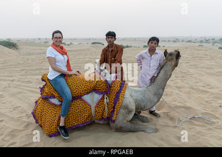 Tourists with camel in desert, Lakhmana Dunes, Damodara, Jaisalmer, Rajasthan, India Stock Photo