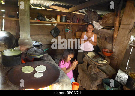 El Salvador  JDS projects in Jujutla.  Family of Alvaro Tejada (60), his wife Agripina Castillo (34) with their daughter Fatima Tejada (6), in village of Los Vasquez, Jujutla. In kitchen making tortillas with 'llorena' eco woodstove. Stock Photo