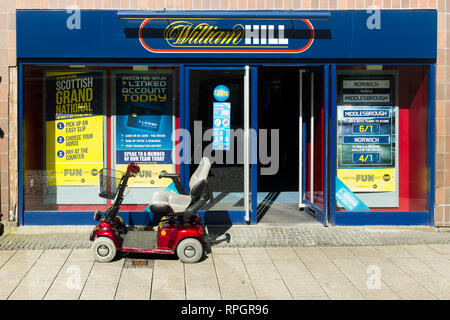 A mobility scooter parked outside William Hill betting shop ,high street Fort William Scottish Highlands Scotland UK Stock Photo