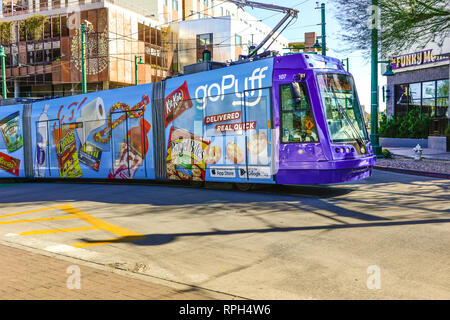 Public transit light rail electric tram on tracks, covered in Advertising banners, in downtown Tucson, AZ Stock Photo