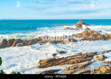 Storm waves crashing into rhyolite rocky foreshore at base of Mount Maunganui looking out to North Rock beacon. Stock Photo