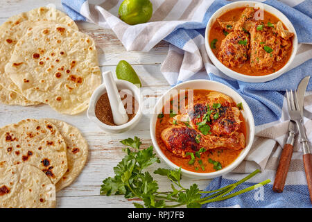 Chicken stewed in creamy spicy Coconut gravy, kuku paka, served on a white bowls on an old wooden table, view from above, close-up Stock Photo