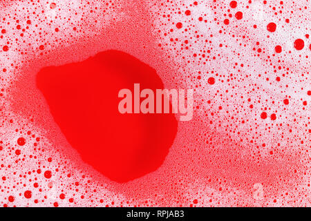 Foam with bubbles on red background. Shampoo or detergent in water. Flat lay. Stock Photo