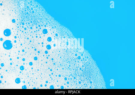 Foam with bubbles on blue background. Soap sud. Detergent in water. Abstract soapy texture. Flat lay. Stock Photo