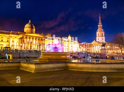 Cityscape view of the famous Trafalgar square of London in evening lights, with colorful fountains and artistic architecture of National Gallery in En
