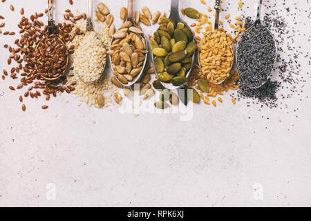 Seeds of pumpkin, flax, sesame, sunflower and poppy in metal spoons on a table, the top view. Food background Stock Photo