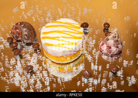 individual vanilla and mango mousse cake on a mirror with crushed ice on a clear background Stock Photo