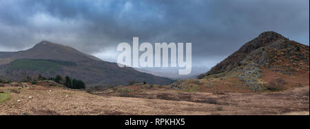 Dark and dramatic Winter landscape image of Moel Saibod from Crimpiau in Snowdonia with stunning shafts of light in stormy weather Stock Photo