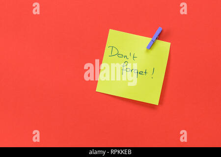 Reminder with text 'Don't forget' on a yellow memo isolated on a red background Stock Photo