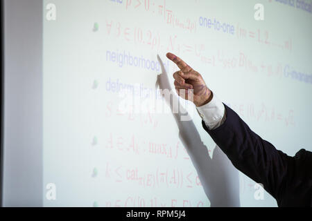 Senior male teacher teaching mathematics, writing on the blackboard Stock Photo