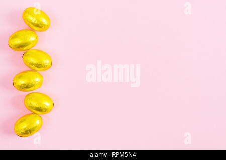 Golden easter eggs over pink background with copy space, flat lay style Stock Photo