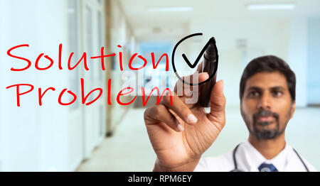 Indian doctor or physician drawing tick with black marker near solution for problem written in red as solving concept on invisible glass screen Stock Photo