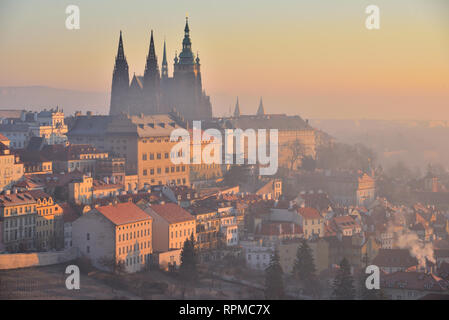 The Prague Castle, St. Vitus Cathedral in Prague, Czech Republic. Early morning. Orange sunrise. Winter. Haze. View from the Strahov Monastery. Stock Photo