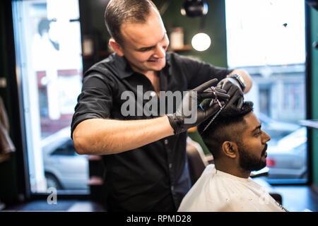 Young handsome guy cuts hair, man cuts hair in barbershop Stock Photo