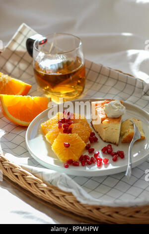 Morning in bed with a piece of cake and some slices of orange with tea on a tray Stock Photo