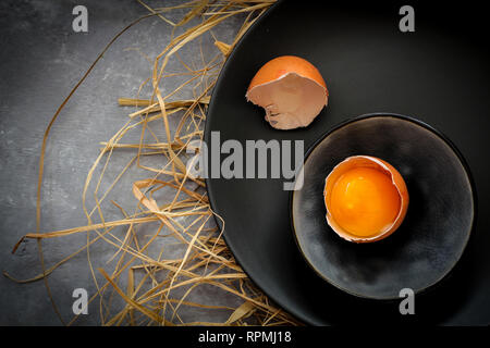 Broken egg on a dark plate on a dark background Stock Photo