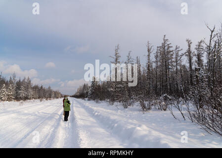 A man and a woman birding on a snow covered road in a cold winter day. Duluth, Minnesota, USA. Stock Photo