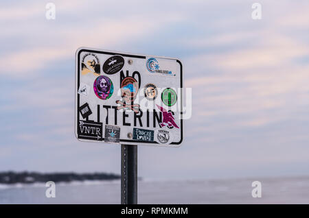 A "No Littering" sign covered by colorful stickers. Duluth, Minnesota, USA. Stock Photo
