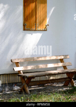 Empty wooden bench near an wall Stock Photo