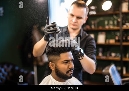Bearded man with long beard, brutal, indian hipster with moustache, with stylish hair, haircut, getting powder on skin with make up brush by barber or Stock Photo