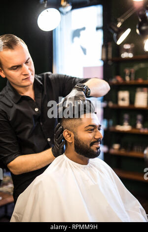Barbers hand spread talcum powder on clients neck with professional shaving brush in barbershop salon.Male beauty treatment concept.Young black man ge