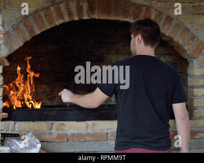 Young man stands in front of barbecue bricks grill Stock Photo