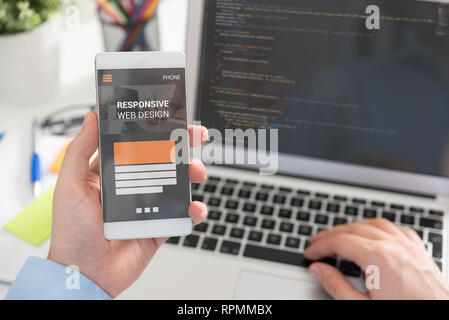 Web designer, programmer working with responsive web template. Multiple devices on desk. Stock Photo