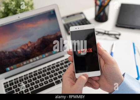 Wroclaw, Poland - JAN 31, 2019: Man holding smartphone with Netflix logo. Netflix is a global provider of streaming movies and TV series Stock Photo